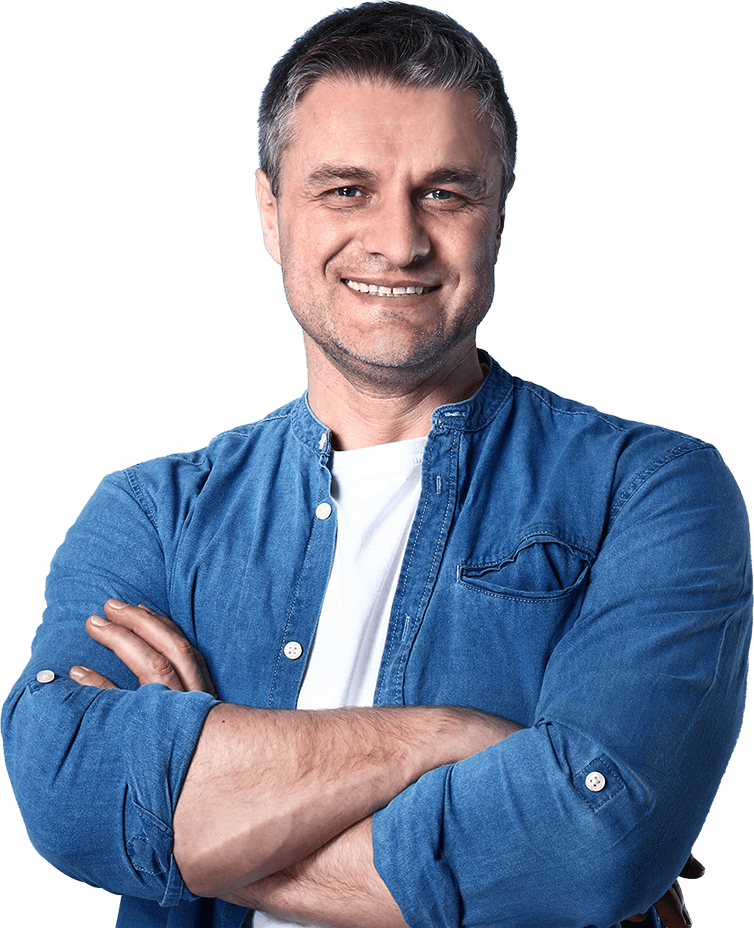 Homem sorridente com cabelos grisalhos, vestindo uma camisa jeans azul sobre uma camiseta branca, com os braços cruzados.